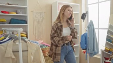 Beyaz bir kadın, giyinme ve aksesuarlarla dolu, parlak, organize bir gardıropta telefonla konuşuyor..