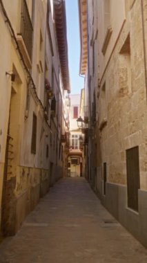 Palma, Mallorca 'daki dar sokaklar, açık mavi gökyüzünün altında eski binalar ve canlı balkonlarla geleneksel İspanyol mimarisini sergiliyor.