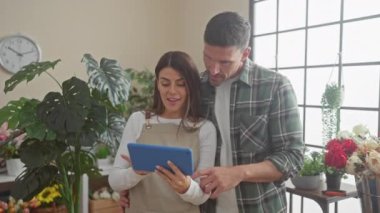 Erkek ve kadın çiçekçiler başarıyı bitki dolu bir çiçekçide beşlikle kutluyorlar.