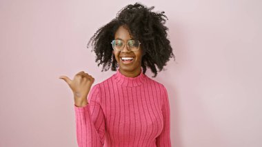 Neşeli siyahi kadın gözlüklü, pembe süveterli, kapalı bir yeri işaret ediyor..