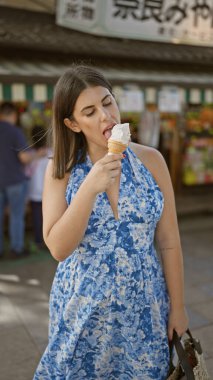 Yaz tatili zevki, güzel İspanyol kadın güneşli bir günde Nara 'da leziz bir dondurma külahının tadını çıkarıyor, Japonya' nın enfes parkı, neşeli gülümsemesi tatil eğlencesi ve açık hava maceralarını yansıtıyor.