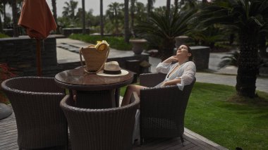 Genç bir kadın, tropikal palmiyelerle çevrili lüks bir bali tatil beldesinde huzurlu bir ortamın keyfini çıkarıyor..