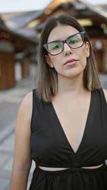 Güzel Latin esmer gözlüklü, Fushimi inari-taisha türbesi, Kyoto 'ya kafayı takmış ciddi bakışlar. Hispano-Japon anı yakalandı, kadın üzüntülü bir güvenle yansıyor, Japon tapınağı.