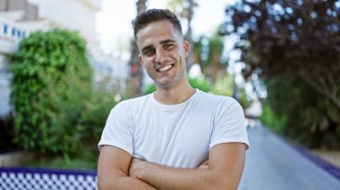 Beyaz tişörtlü neşeli, genç bir İspanyol, yemyeşil bir parkta güvenle dikiliyor..