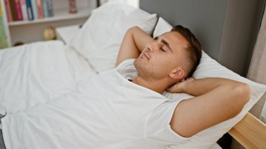 Yatakta, gözleri kapalı, huzurlu bir yatak odası ortamında dinlenen genç bir adam..