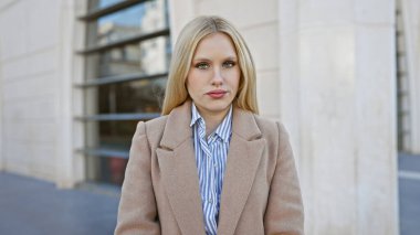 Profesyonel kıyafetli kendine güvenen genç bir kadın şehrin bir caddesinde duruyor zarafet ve kararlılıkla.