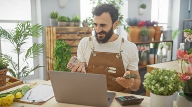 Sakallı adam yemyeşil bir çiçekçide uae dirhams sayıyor.