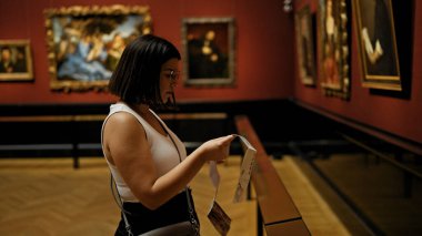 Güzel İspanyol bir kadın sanat galerisini ziyaret edip Viyana 'daki Sanat Müzesi' nde broşür okuyor.