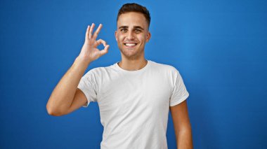 Gülümseyen genç İspanyol adam mavi arka planda 