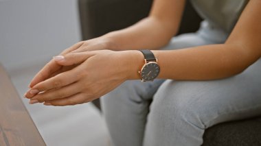 Modern bir ofis ortamında şık bir saatle bir kadının katlanmış ellerine yakın çekim.