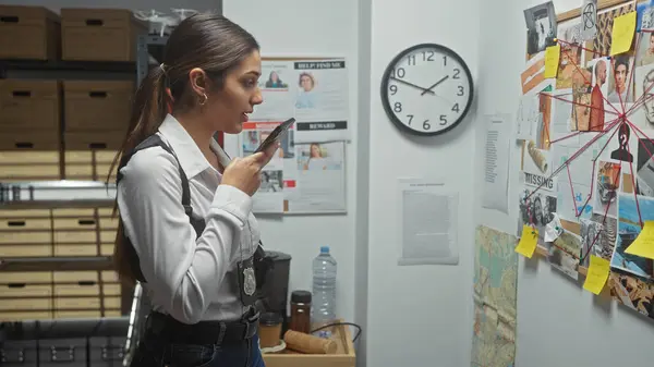 stock image Hispanic woman detective analyzes evidence at police department board indoors.