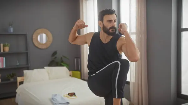 stock image A mature man with a beard stretching in a bedroom, exuding health and focus, in an interior fitness scenario.