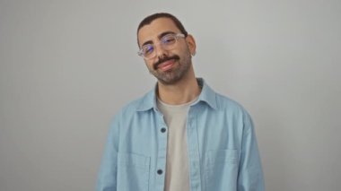 Kotlu tişört giyen genç İspanyol bir adam. Elinde iyi bir işaret, gülümsüyor ve izole edilmiş beyaz arka plan üzerinde dostça bir parmak işareti taşıyor. Mükemmel ve kendinden emin.