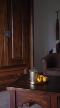 Eski bir gümüş kap ve olgun portakallar ahşap bir masa üzerinde klasik bir iç mekan ve deri bir koltuk..