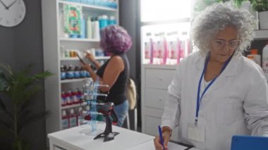 Eczanede orta yaşlı bir kadına yardım eden yaşlı bir eczacı, eczane rafları ve tıbbi gereçlerle...
