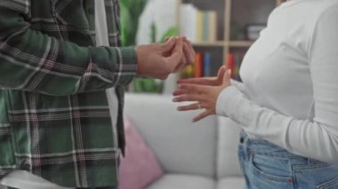 Bir erkek ve kadının kapalı alanda sevgiyle el ele tutuşması, ev ortamında sevgi ve ortaklık hissi uyandırıyor..