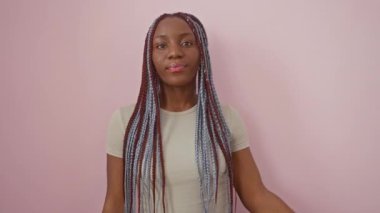 Neşeli bir Afro-Amerikan kadını, parmakları yüzünde bir barış sembolü çırpınırken, kulaklarından kulağa sırıtıyor, zaferin simgesi, pembe bir arka planda izole edilmiş..