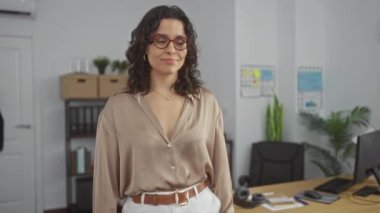 Ofis ortamında kolları çaprazlanmış bir İspanyol kadın profesyonel bir kurum ve görünür ofis malzemeleriyle kapalı bir iş yerinde bulunuyor..