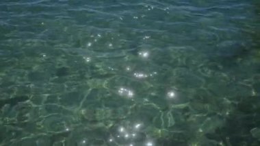 Güneş ışığı, porto sezaryenin berrak yeşil sularında parıldıyor. Salento, İtalya. Parlak gün ışığında okyanus dalgalarının güzelliğini gözler önüne seriyor..