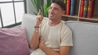 Heyecanlı, evdeki kanepede kendinden emin bir şekilde oturan genç İspanyol, neşeli bir yüz takınıyor. Mutlu ve şaşırmış bir bakışla işaret ediyor. Akıllıca bir fikri ya da hileli bir sorusu var.!