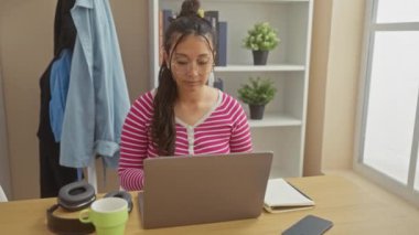 Genç bir İspanyol kadın evinde rahatlıyor, rahat bir oturma odasında dizüstü bilgisayarını kullandıktan sonra gözlüklerini çıkarıyor..