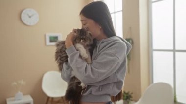 Genç Asyalı bir kadın parlak, aydınlık bir veteriner bekleme odasında tüylü kedisine sarılıyor, sıcaklığı ve ilgiyi yansıtıyor..