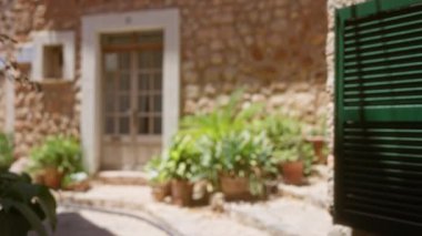 Mallorca İspanya 'daki saksılarda yeşil bitkiler bulunan geleneksel taş evin arka planının çözülmüş hali.
