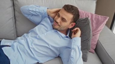 Rahat bir İspanyol adam rahat bir oturma odasında rahat bir kanepede dinleniyor..