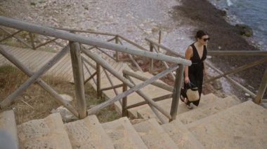 Siyah elbiseli Hispanik kadın, İspanyol Mallorca, İspanya 'da, Port de Valldemossa kıyısında taş merdivenlerden yukarı çıkıyor..