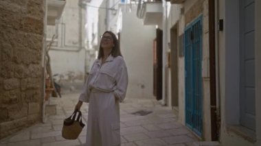 Polignano 'nun büyüleyici sokaklarında bir kısrak, puglia, İtalya' da elinde kamış çantasıyla gezen ve Avrupa 'nın güzel ortamında gülümseyen şık bir İspanyol kadın..