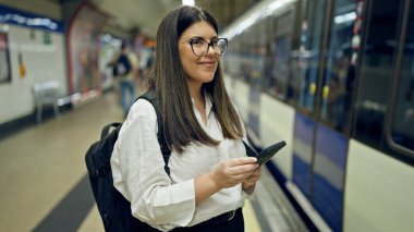Madrid metro istasyonunda akıllı telefon kullanan güzel İspanyol bir kadın metroda bekliyor.