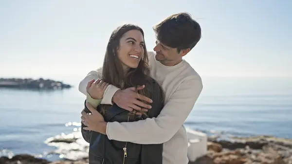 stock image A loving couple embraces by a tranquil sea, exuding romance and happiness in a picturesque outdoor setting.