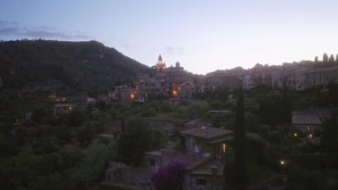 Akdeniz mimarisi ve yemyeşil yeşillikleri gözler önüne seren, Mallorca, İspanya tepelerinde yuvalanmış aydınlık evlerle dolu deia 'nın pitoresk köyüne gece çöküyor..