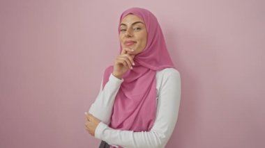 Genç İspanyol kadın tesettüre binmiş gülümsüyor kameraya kollarını kavuşturup çenesini kapatarak bakıyor. Olumlu düşünüyorum. izole edilmiş pembe arkaplan