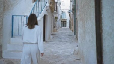 Polignano 'da pitoresk sokaklarda yürüyen genç bir kadın bir kısrak, puglia, italyan, tarihi beyaz binalar ve mavi aksanlar sergiliyor..