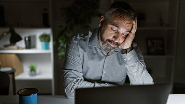 Karanlık bir ofiste gri sakallı yorgun bir İspanyol gece bitkin görünüyor.