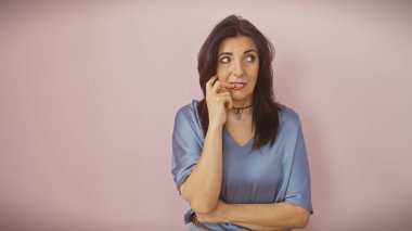 Mavili düşünceli olgun İspanyol kadın pembe arka planda, düşüncelere ve zarafete bürünüyor..