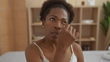 Bir kaplıcada yeşim taşı kullanan Afrikalı Amerikalı bir kadın. Kapalı bir salondaki güzellik ve refahı gösteriyor. Arka planda cilt bakımı için sağlık ürünleri var..