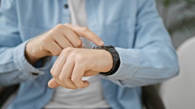 Profesyonel bir adam bir ofis ortamında kol saatini kontrol eder, dakiklik ve sorumluluk taşır..