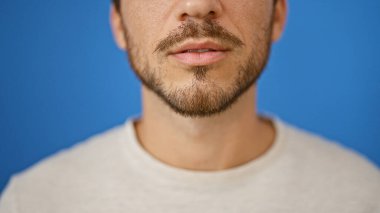 Mavi arka planda sakallı yakışıklı bir İspanyol 'un yakın plan portresi.