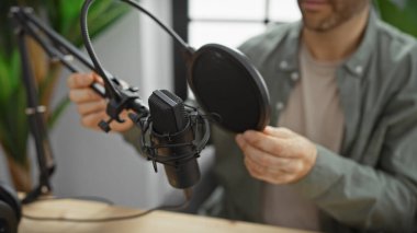 Genç bir İspanyol, radyo stüdyosunda mikrofon ayarlıyor. Modern yayıncılığın örneğini veriyor..