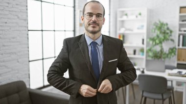 Kendine güvenen kel iş adamı, modern ofiste kravatını düzeltiyor, liderlik ve profesyonelliği somutlaştırıyor..