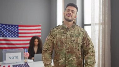 Askeri üniformalı bir adam, seçim merkezinde bir kadınla birlikte demokratik katılımı ve vatanseverliği ifade eden 