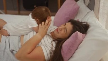 Sıcak yatak odasında bebeğe sarılan bir kadın, kapalı bir ortamda sevgi ve aile bağını somutlaştıran, anne sevgisini ve sıcaklığını vurgulayan bir kadın..