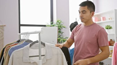 İspanyol bir adam parlak modern bir odada kıyafet seçiyor, yaşam tarzını ve moda seçimlerini yansıtıyor..