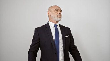 Takım elbiseli, kel ve seçkin bir adam beyaz bir geçmişe karşı duruyor. Olgunluk ve profesyonellik yayıyor..