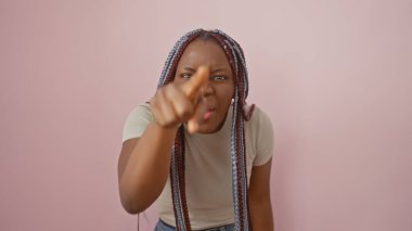 Örgü örgülü Afro-Amerikalı bir kadın pembe izole bir arka planda kameraya bakıyor.