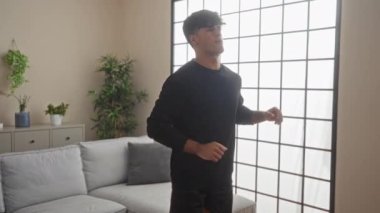 Genç İspanyol bir adam, şık bir oturma odasında, bitkilerle ve modern dekorla egzersiz yapıyor. Evinde spor yapıyor..