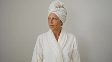 Sessiz ve gizli. Havlu ve bornoz giyen orta yaşlı kadın. Sessiz bir jest için parmaklarını dudaklarına koy.