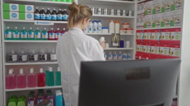 Beyaz önlüklü beyaz bir kadın eczacı modern bir eczanede ilaçları inceliyor..